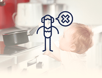 A baby is looking at an oven with a person in the background.